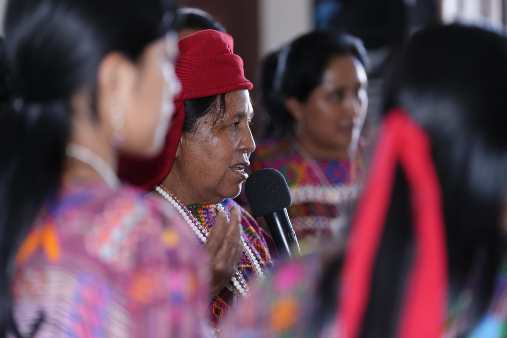 Una mujer hablando al micrófono en una asamblea indígena en Guatemala